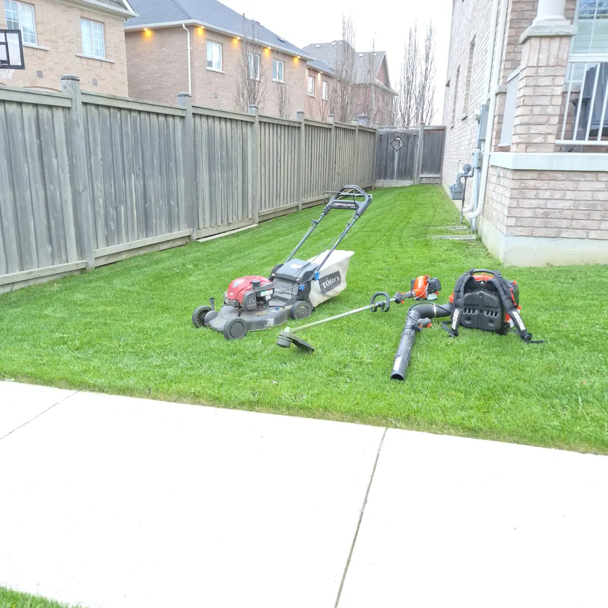 Commercial mower, trimmer and backpack blower staged on a freshly cut lawn.